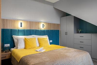 Premium Suite at Rezydencja AMBRE, Łeba – bedroom with teal headboard and yellow cushions