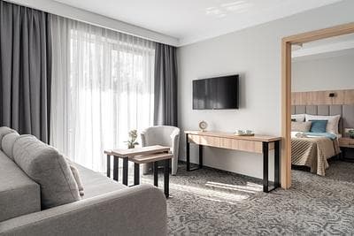 Suite at Rezydencja AMBRE, Łeba – living area with grey sofa, armchair and desk, separate bedroom next door